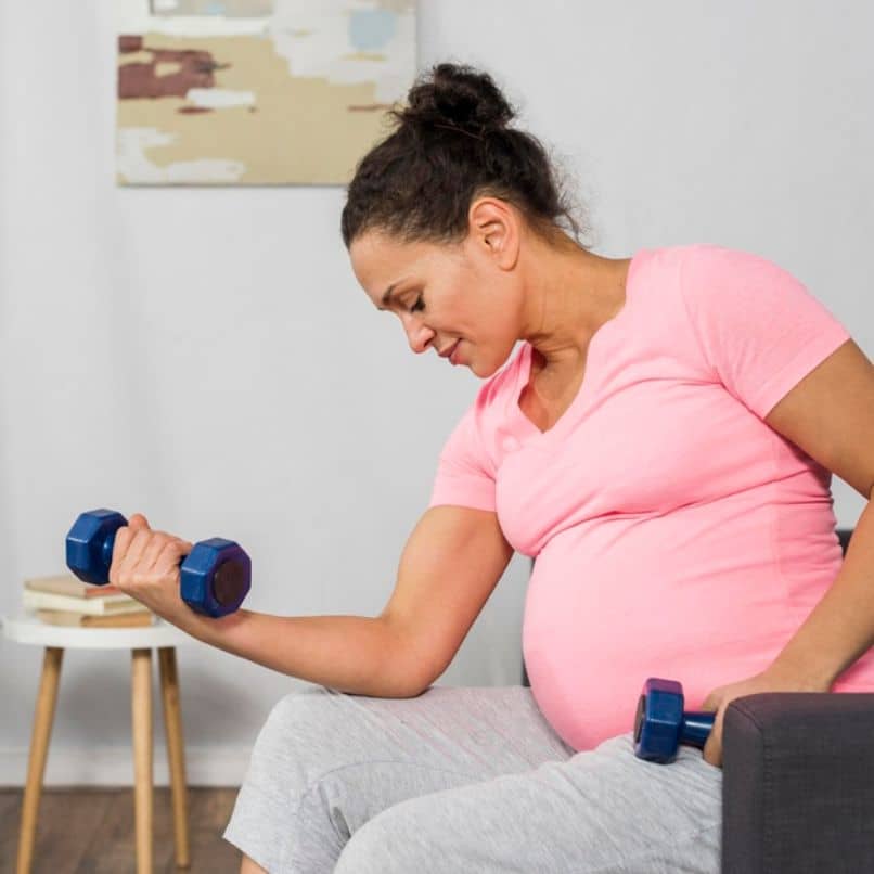 embarazada cargando pesas como rutina de ejercicios 